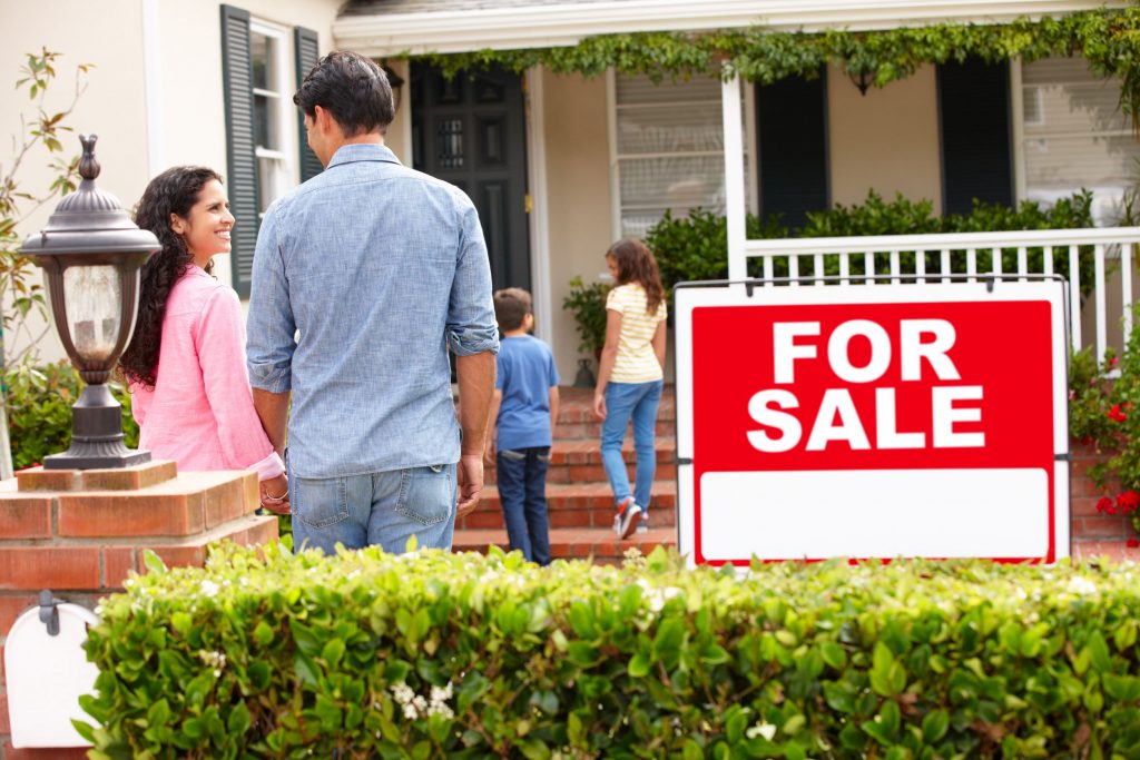 Family walking into house with for Sale sign out front