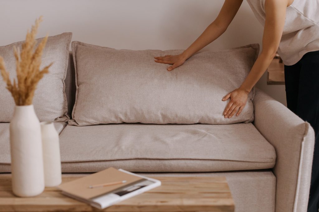 Hands of person tidying couch preparing home for sale